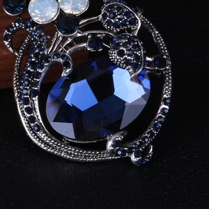 Macro detail of vintage brooch with deep blue oval gemstone and white opal accents