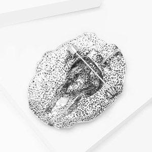 Detailed macro view showing the textured silver alloy back and safety pin clasp of the brooch