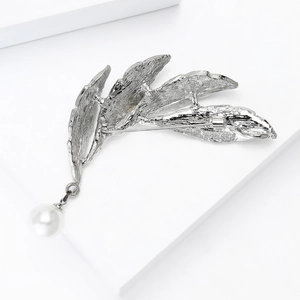 Elegant silver leaf brooch with white pearl pendant on minimalist geometric blocks