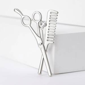Detailed view of silver hair stylist brooch featuring scissors, comb, and a sparkling zircon