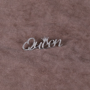 Macro shot of silver Queen brooch featuring a crown design and sparkling pavé crystals