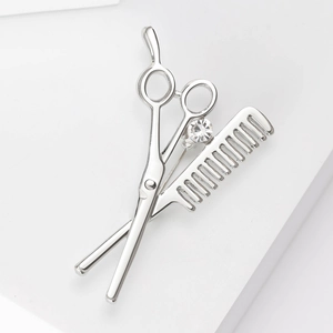 Detailed macro view of silver scissors and comb brooch featuring a sparkling rhinestone