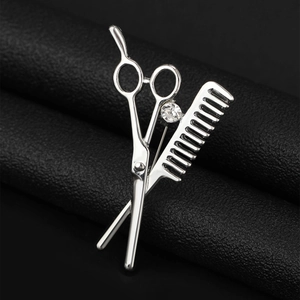 Detailed close-up of a silver scissor and comb brooch with a sparkling zircon on black leather