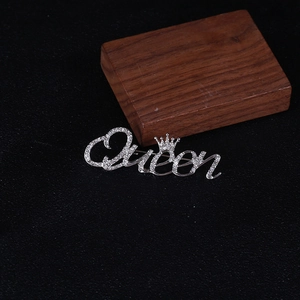 Macro detail of silver Queen letter brooch with crown and pavé rhinestone setting