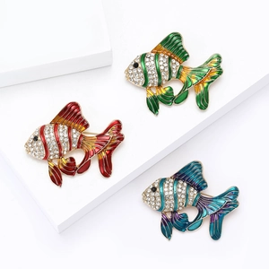 Trois broches poissons émaillées colorées avec strass sur présentoir géométrique blanc