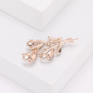 Détail d'une broche fleur or rose avec perles blanches et fermoir en métal au dos