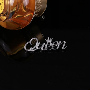 Detail of silver Queen brooch with crown and diamonds on a luxury black background