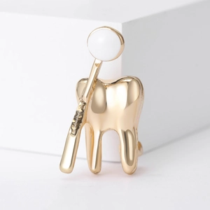 Broche dentaire créative en or avec miroir pour professionnels de santé sur fond blanc