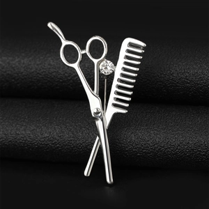 Macro shot of silver scissors and comb brooch with rhinestone on black leather