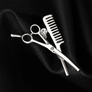 Detailed macro of silver barber brooch with scissors, comb and sparkling crystal