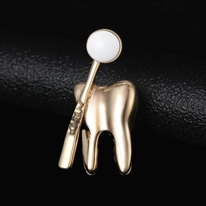 Vue détaillée d'une broche en forme de dent dorée et miroir dentaire sur fond de cuir noir