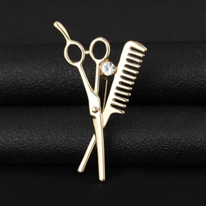 Macro shot of gold barber brooch featuring scissors and comb with zircon inlay
