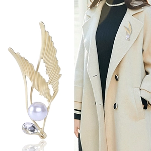 Elegant matte gold angel wing brooch with pearl and diamond accents on coat