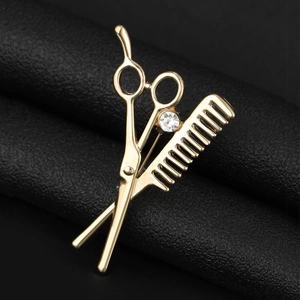 Macro detail of gold barber scissor and comb brooch with sparkling zircon on black leather