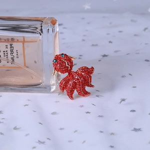 Détail macro de la broche carpe koi en strass rouges avec des yeux en cristal vert