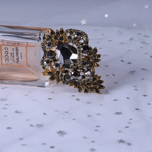 Detailed macro view of vintage rhinestone brooch with black pear-shaped gemstone and gold base
