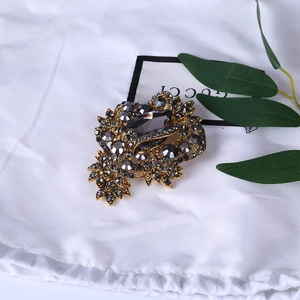 Macro detail of vintage gold floral brooch with grey rhinestones and drop crystal