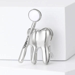 Détail d'une broche dentaire en argent avec dent et miroir en émail blanc sur socle blanc