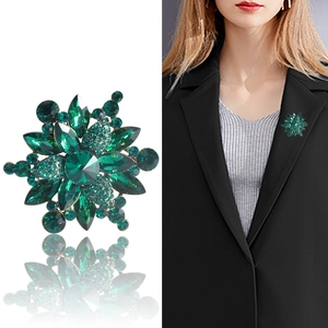 Detail of green crystal floral brooch on black blazer with a high-end jewelry reflection
