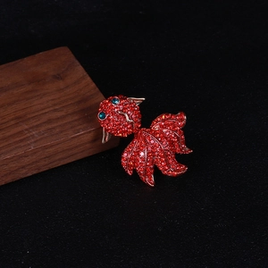 Détail de la broche carpe koi dorée avec strass rouges et yeux en pierres précieuses vertes