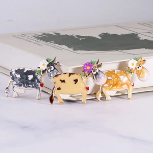 Three-piece set of cartoon cow enamel pins with floral details and heart accents