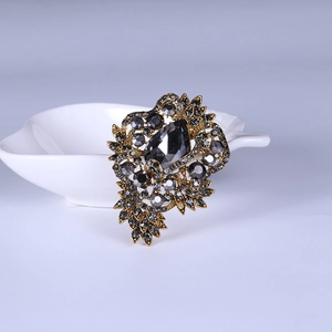 Detailed macro view of vintage gold flower brooch with dark grey rhinestones on petals