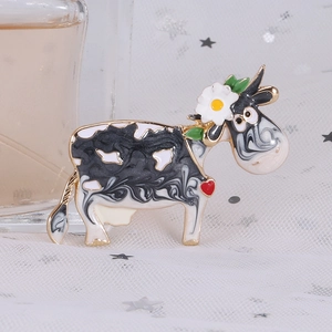 Detailed view of the cow-shaped enamel brooch with floral accents on white lace