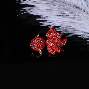 Gros plan d'une broche carpe koï rouge sertie de strass et d'yeux en gemmes vertes