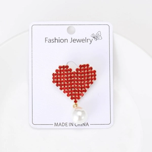 Detail of red heart brooch with crystals and hanging pearl on a jewelry card