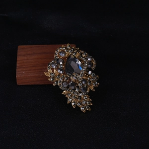 Macro detail of a vintage gold-toned brooch with a large teardrop grey stone and rhinestones