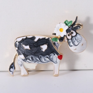 Detailed close-up of cow brooch with black and white enamel pattern and floral accent