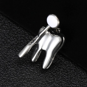 Broche dentaire en argent poli avec une dent et un miroir sur fond de cuir noir