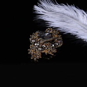 Close-up of vintage gold rhinestone brooch with grey crystals on reflective black surface
