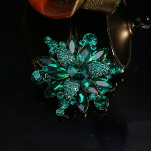 Macro shot of luxury star-shaped crystal brooch with emerald green stones and gold plating