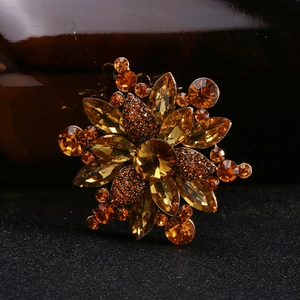 Macro shot of an amber crystal flower brooch with rhinestone petals and gold metal base