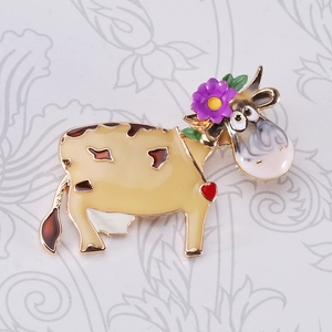 Detail of cartoon enamel cow brooch with purple flower and heart patterns on base