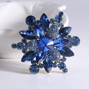 Macro shot of blue crystal flower brooch with rhinestone accents on a white bowl