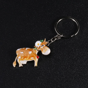 Detailed macro view of a cute cartoon cow enamel keychain with white flower and red heart