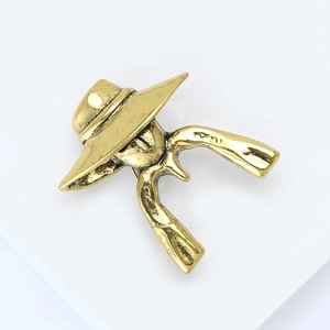 Vintage gold metal portrait brooch with hat and boots motifs on a clean background