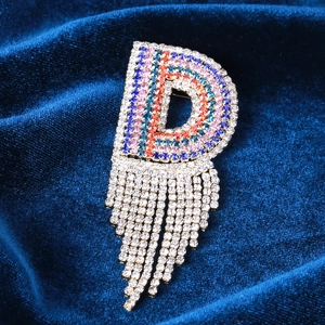 Dettaglio spilla a forma di D di lusso con strass colorati e nappe di cristallo