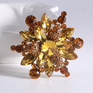 Close-up of snowflake brooch with amber and champagne crystals on a white ceramic base