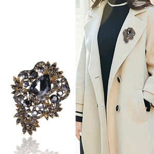 Vintage gold brooch with grey crystal flower design shown on model for style and size