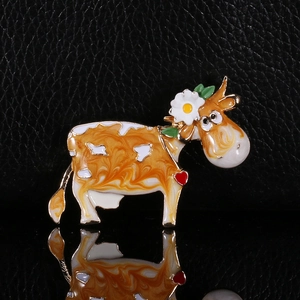 Macro view of cartoon cow enamel brooch with flower detail and marbled texture