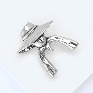 Close-up of vintage silver western cowboy brooch featuring a wide hat and revolvers