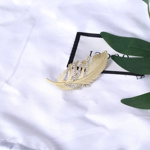 Élégante broche plume dorée avec strass scintillants et finition métallique texturée
