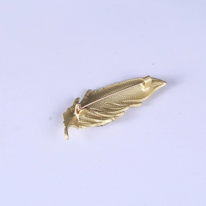 Vue arrière de la broche plume dorée avec fermoir de sécurité et texture métal mat