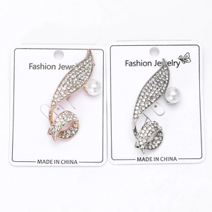Detail view of streamlined rhinestone brooches with faux pearls in gold and silver