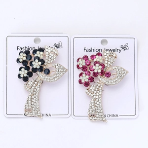 Détail de broches florales avec strass bleus et magenta sur une carte de présentation