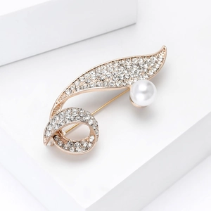 Close-up of elegant gold brooch with sparkling rhinestones and a white pearl accent