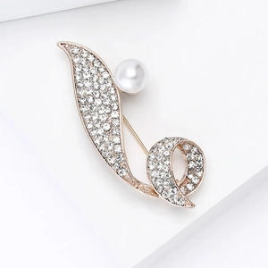 Detailed view of luxury gold brooch with rhinestones and a large white pearl centerpiece
